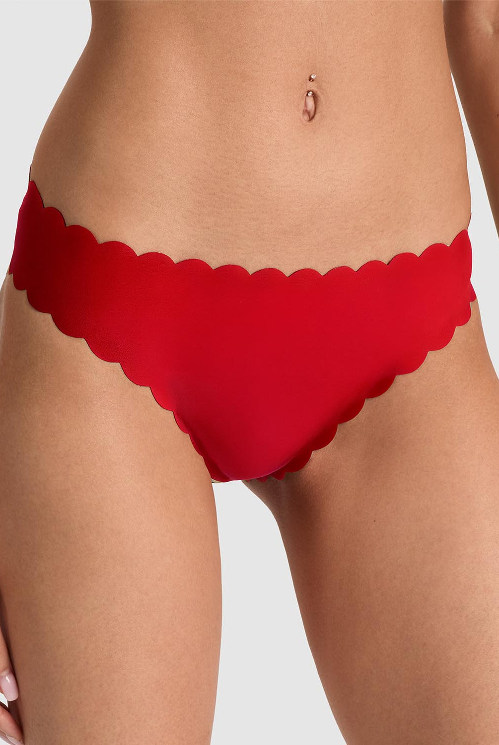 Red scalloped-edge bikini bottom worn by a model, shown from the waist to upper thighs against a light gray studio background.