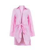 A long sleeve pink cover up against a white wall.