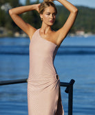 A blonde woman wearing a dress standing near the water.