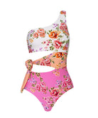 A floral one piece swimsuit against a white wall.