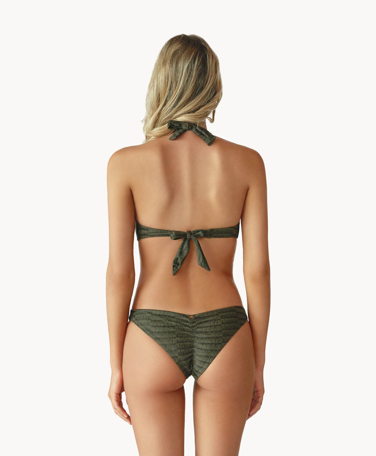 Blonde woman wearing a gray print halter bikini with ring detail facing backwards towards a white wall.