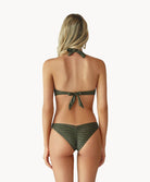 Blonde woman wearing a gray print halter bikini with ring detail facing backwards towards a white wall.