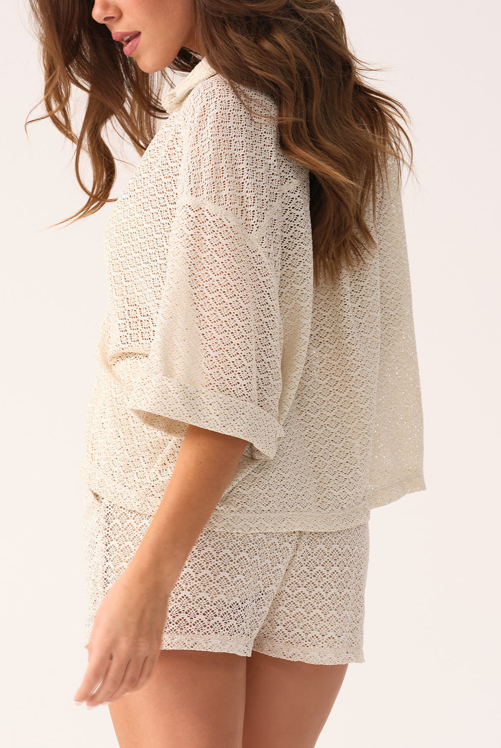 Woman wearing a white lace outfit on a plain background