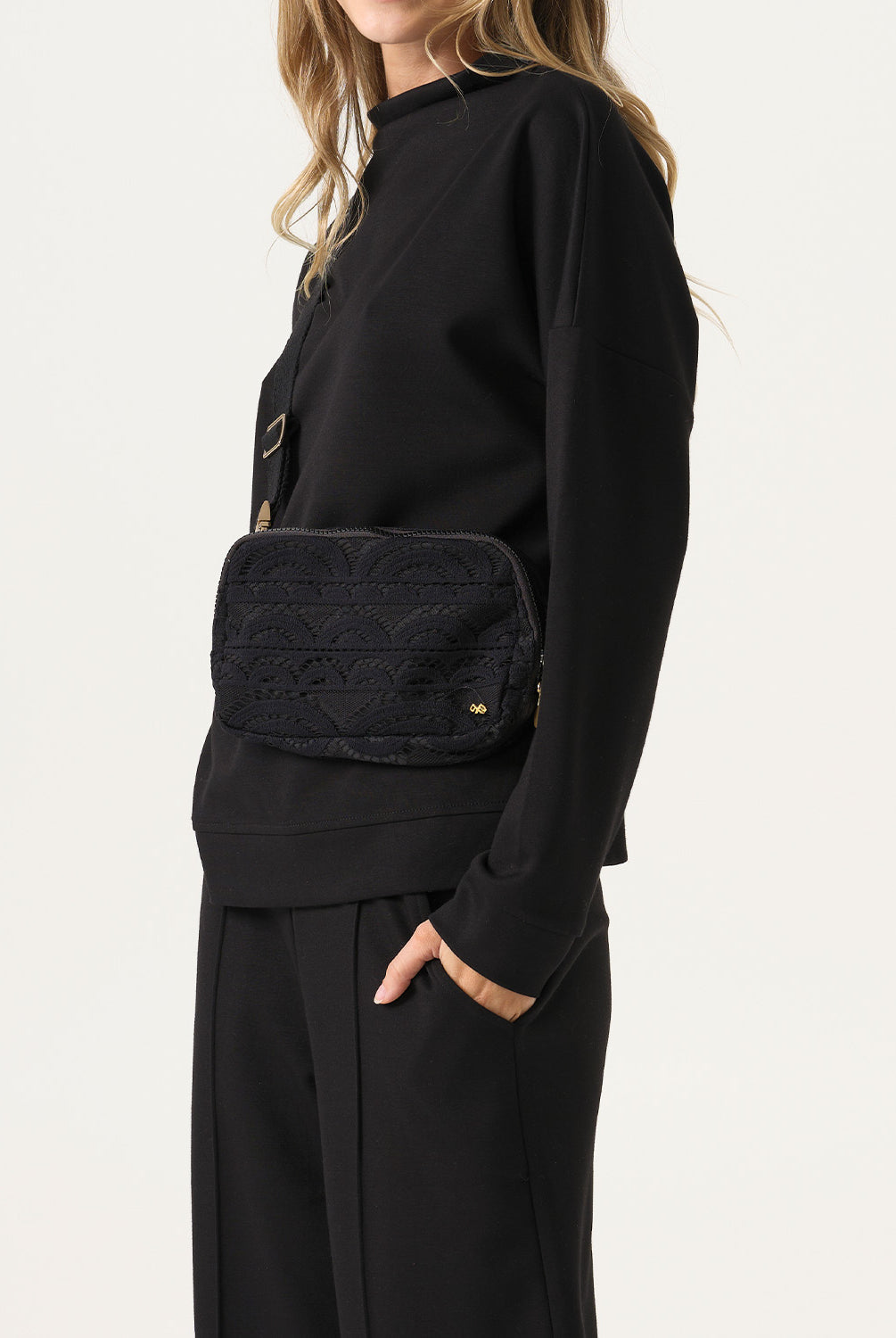 Woman wearing a black outfit with a quilted black bag on a white background