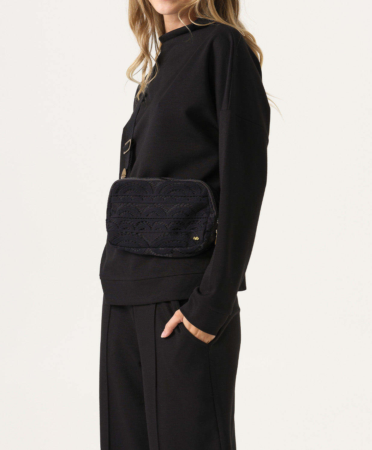 Woman wearing a black outfit with a quilted black bag on a white background