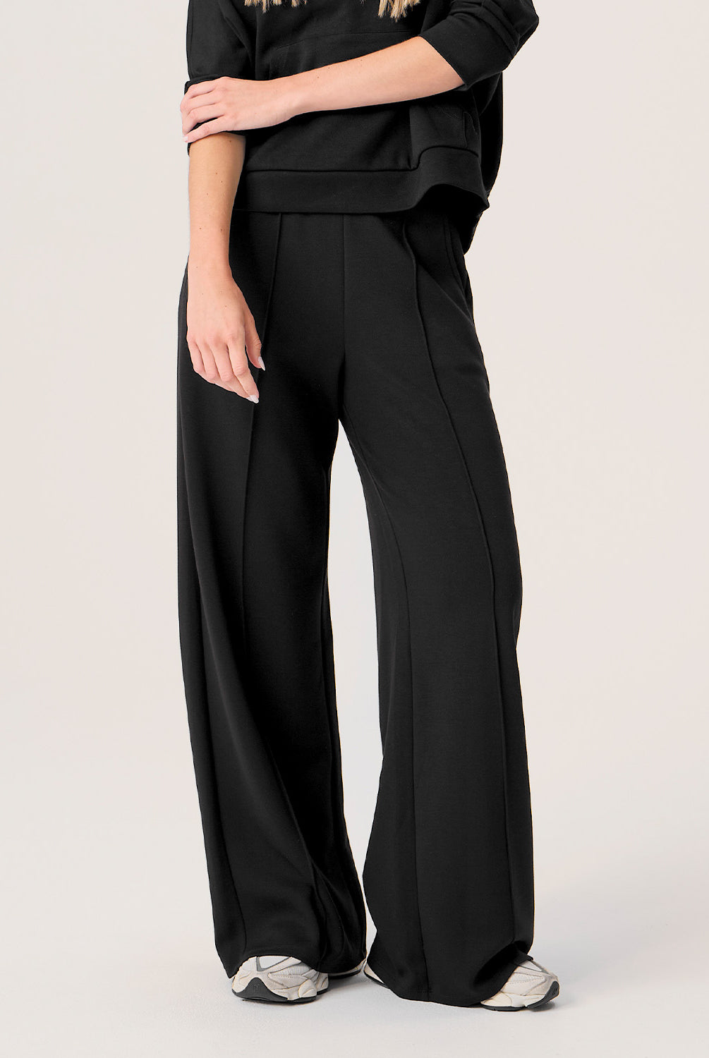 Woman wearing black wide-leg pants on a plain background