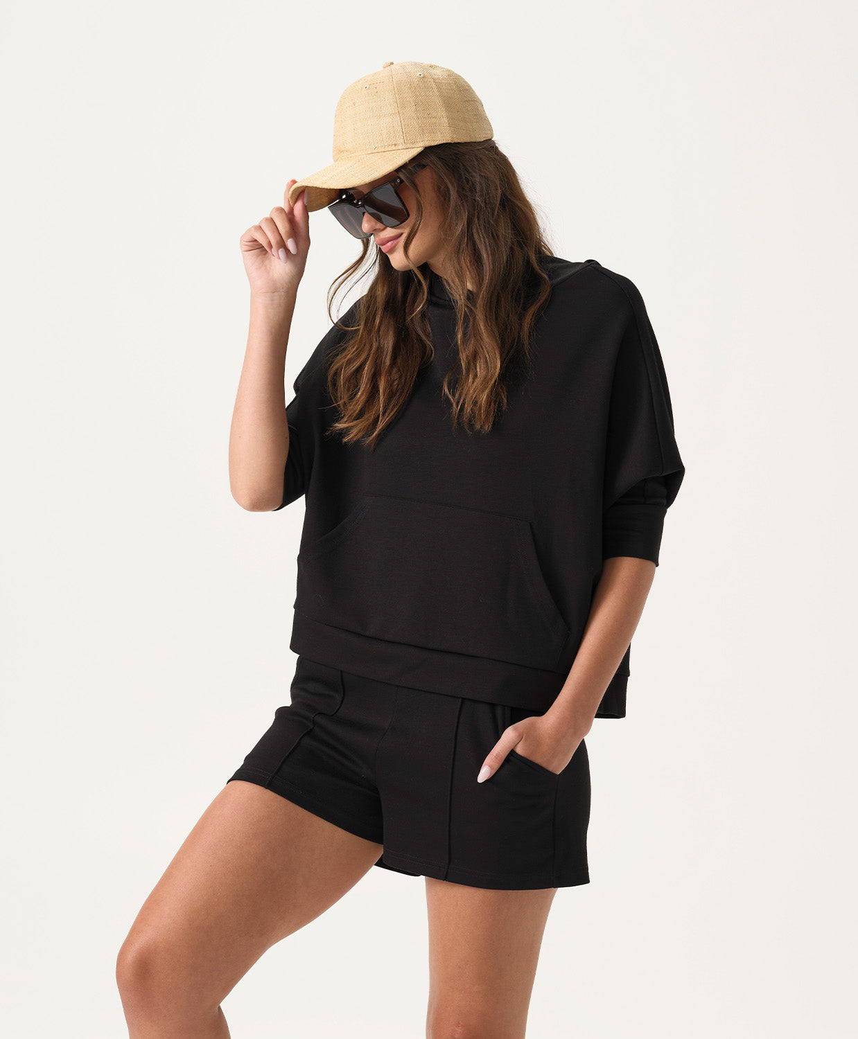 Woman wearing a black outfit with a beige cap on a white background