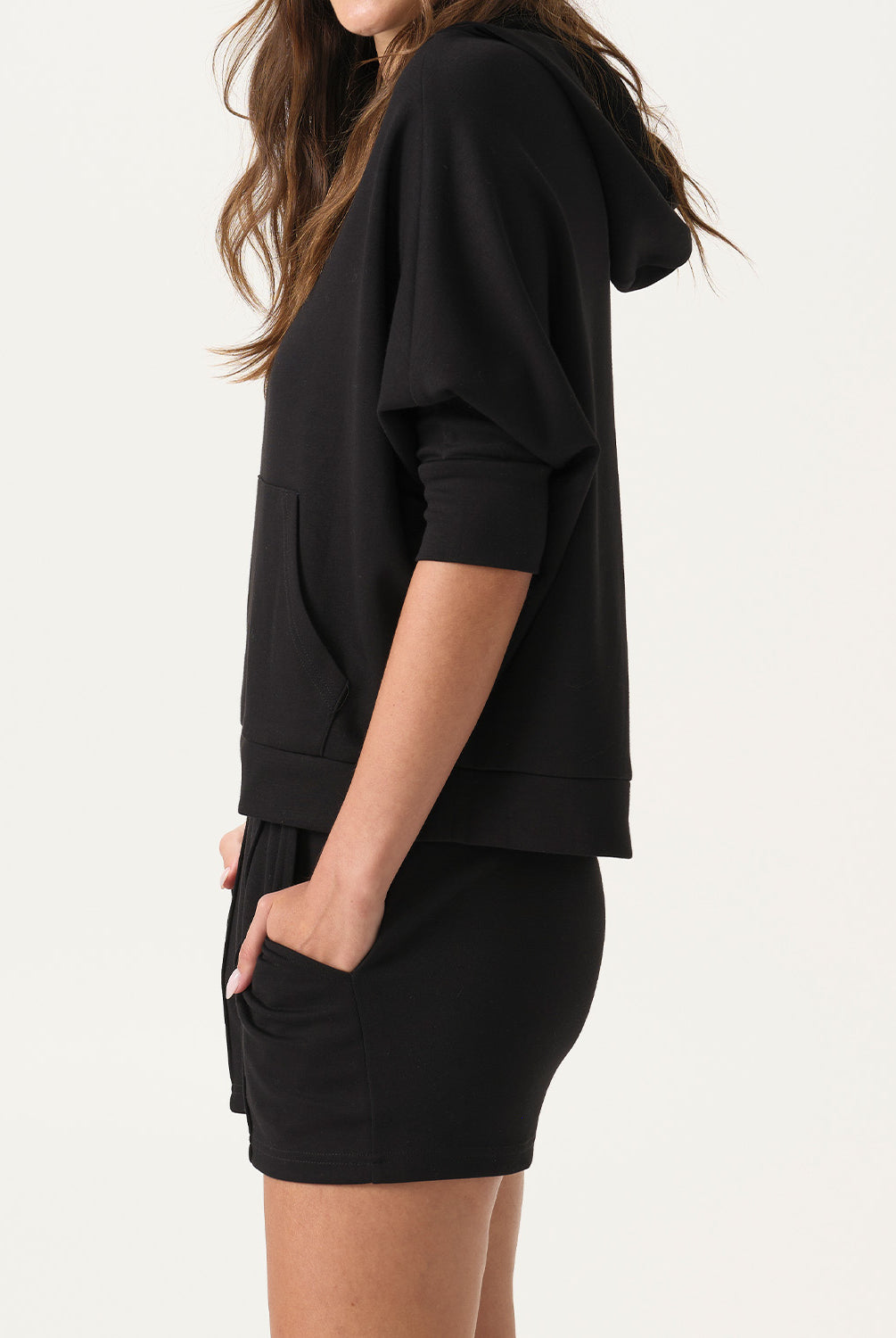 Woman wearing a black hoodie and shorts set on a white background