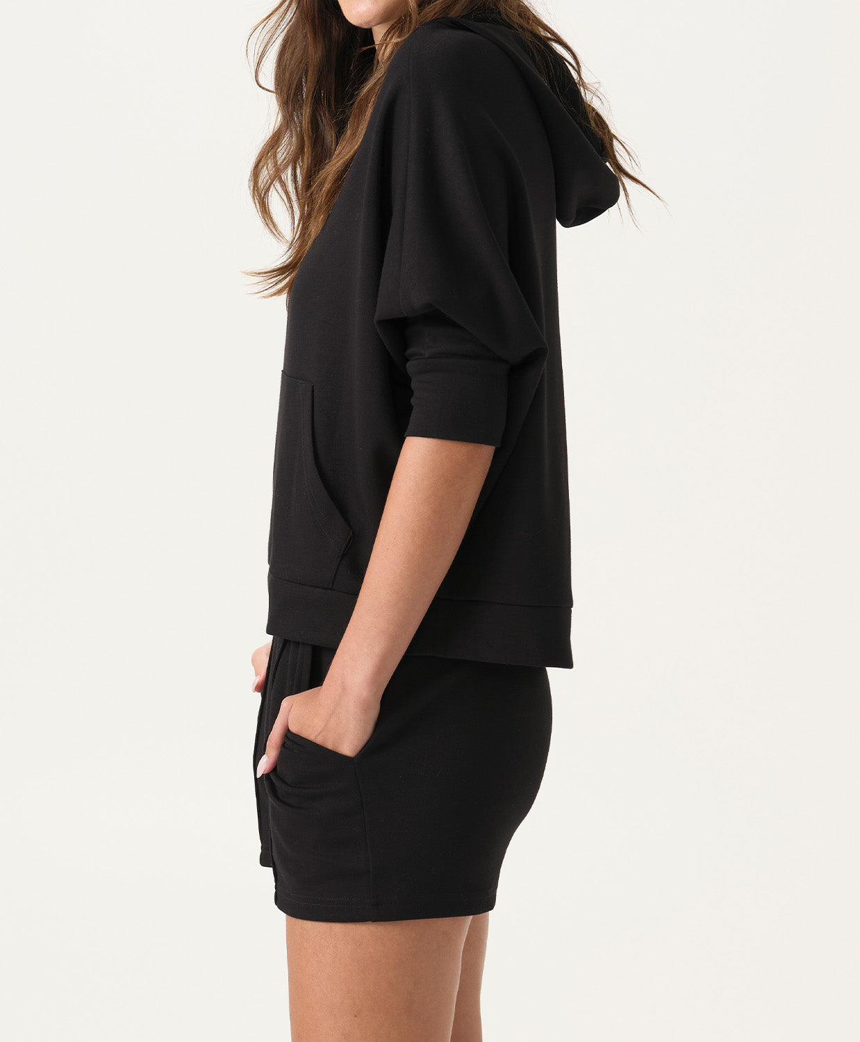 Woman wearing a black hoodie and shorts set on a white background