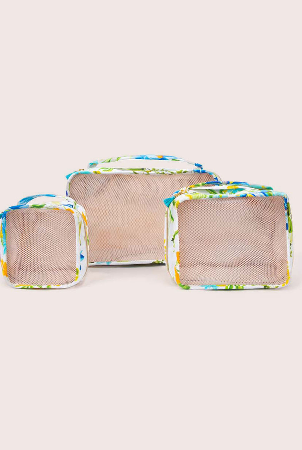 A set of three packing cubes against a white wall.