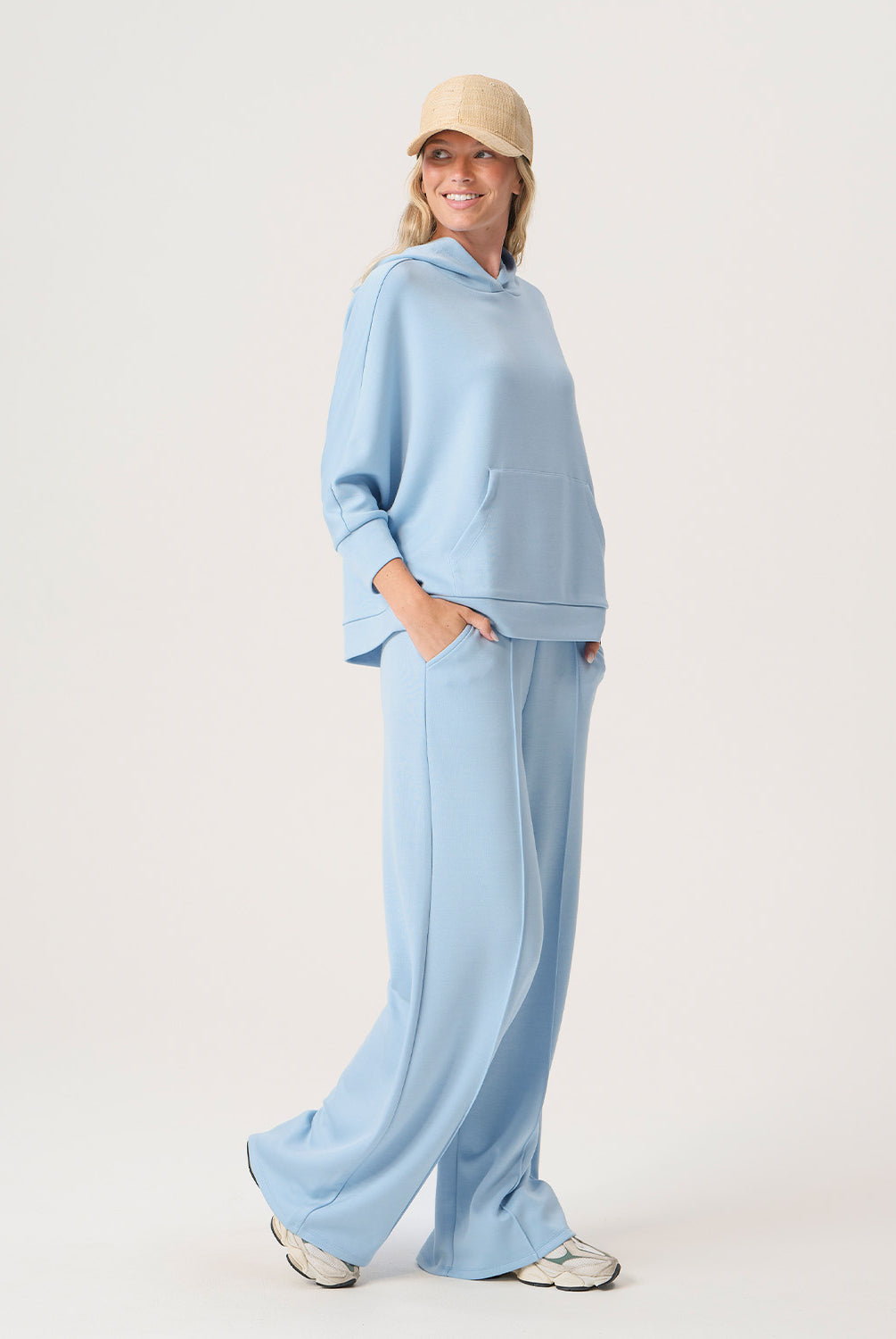 Woman wearing a light blue outfit with a matching cap on a white background