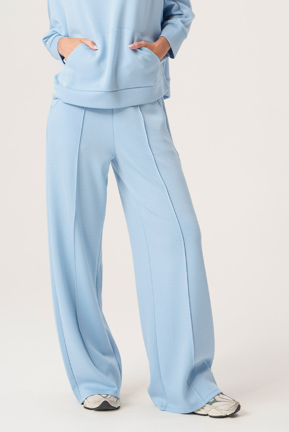 Woman wearing a light blue outfit with wide-leg pants on a white background