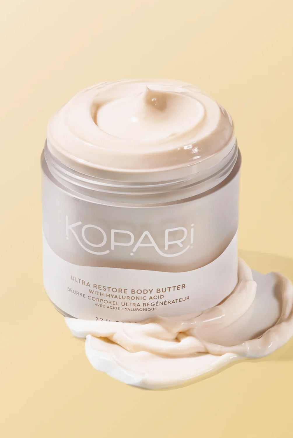 A jar of opened body lotion against a yellow wall.