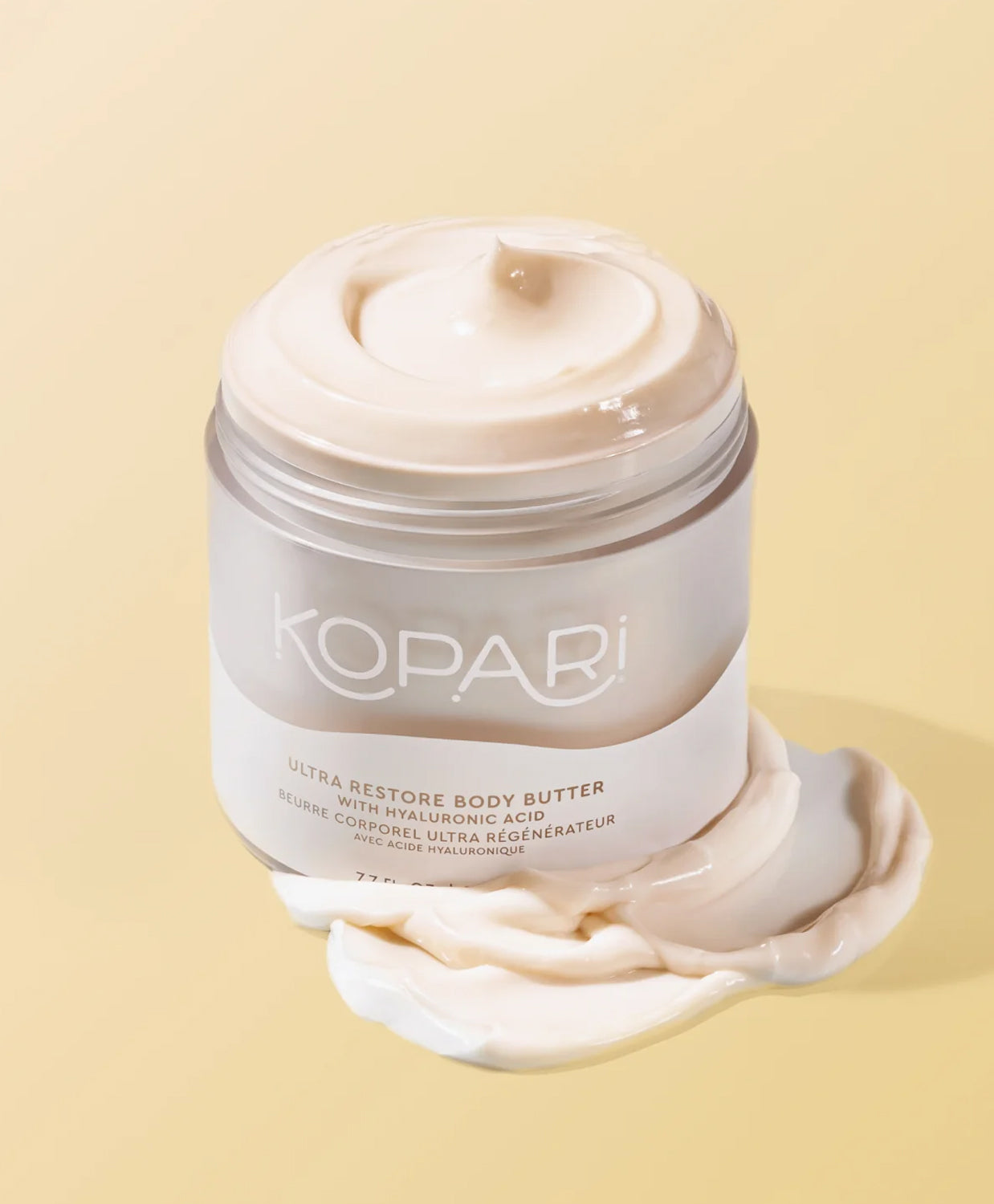 A jar of opened body lotion against a yellow wall.