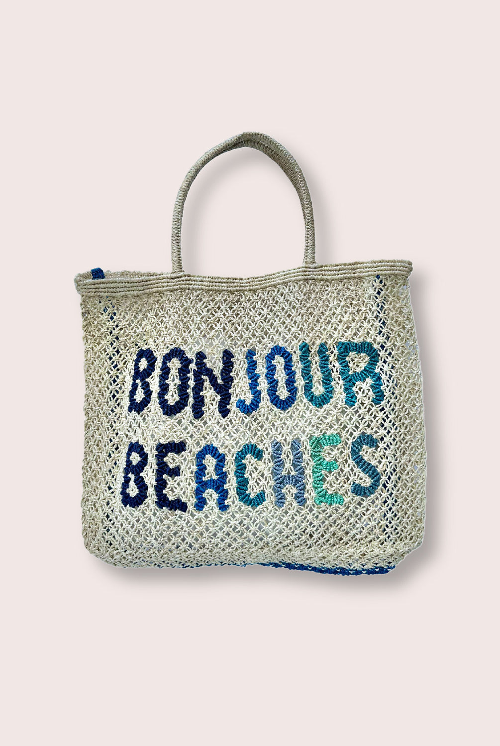 A purse/tote that says "Bonjour Beaches" in blue against a white wall.