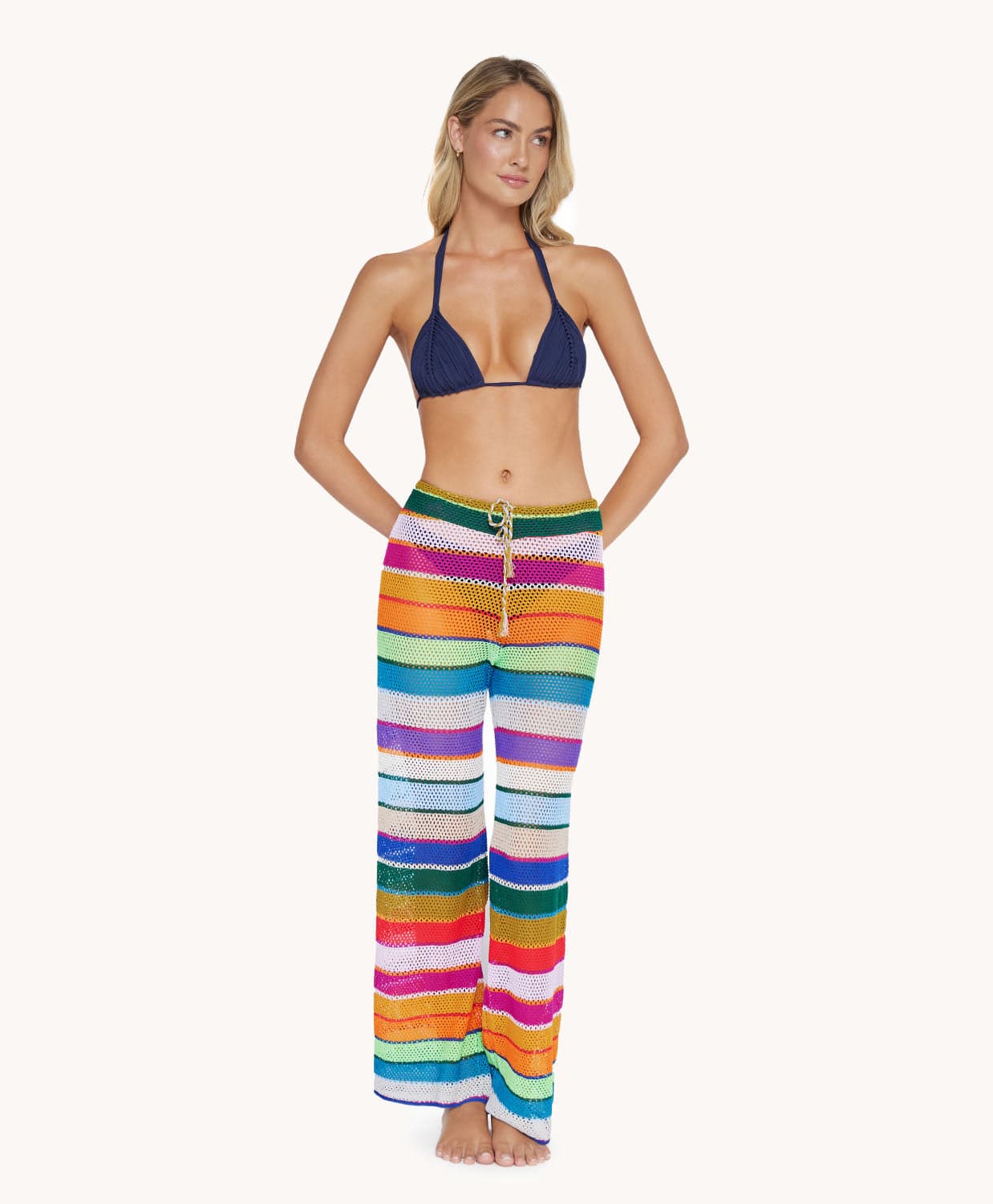 A blonde woman wearing a navy bikini top and color block pants standing in front of a white wall.