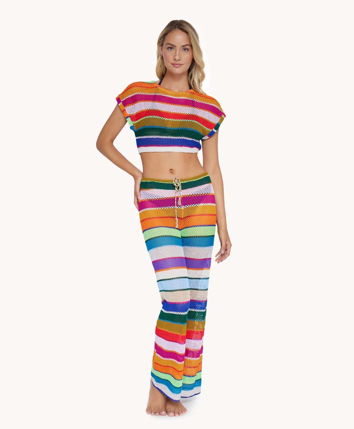 A blonde woman wearing a color block top and pant set standing in front of a white wall.