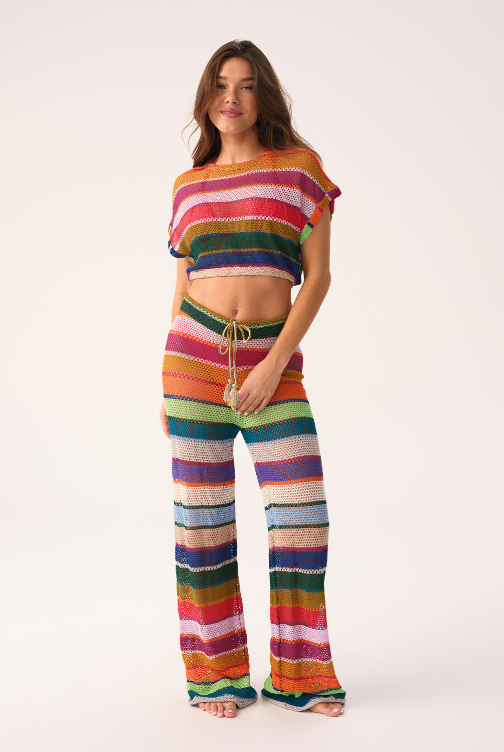 Woman wearing a colorful striped crochet outfit on a white background