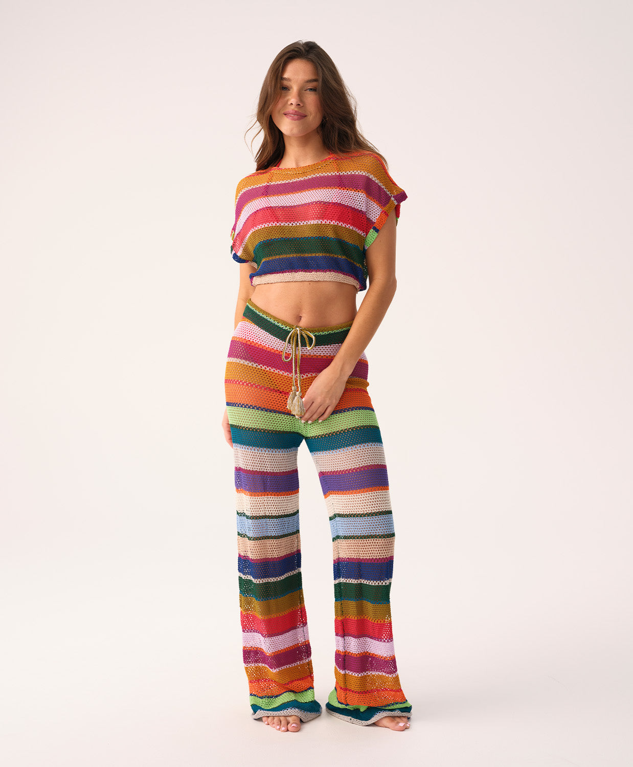 Woman wearing a colorful striped crochet outfit on a white background