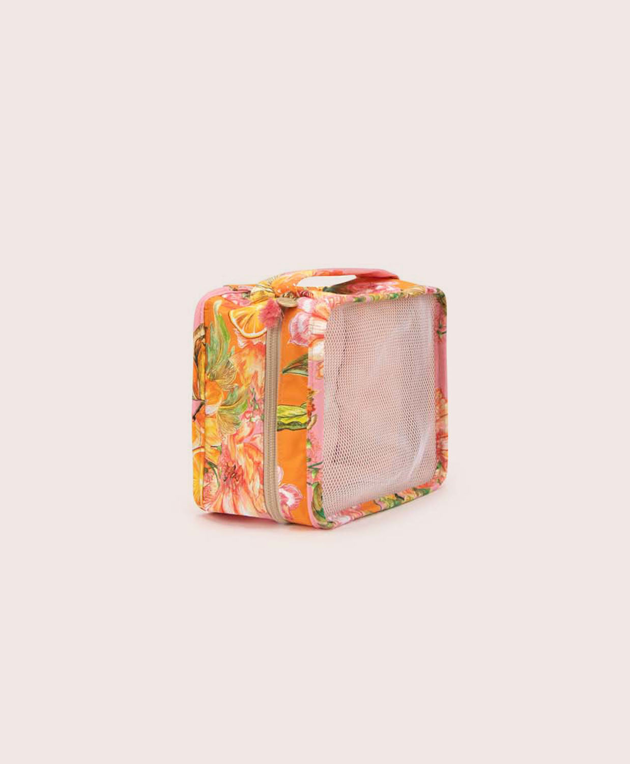 A packing cube with an orange floral print against a white wall.
