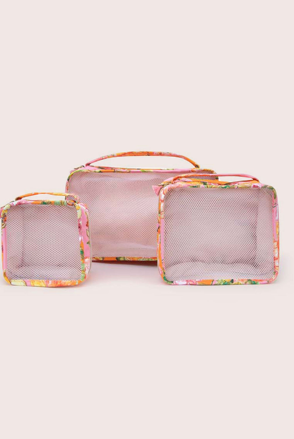 A set of three packing cubes against a white wall.