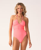 Woman wearing a pink halter neck swimsuit on a white background