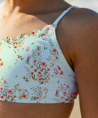 Floral-patterned bikini top worn by a young girl on a beach.