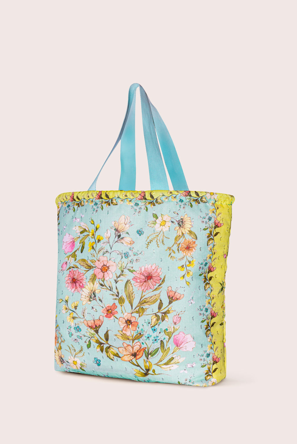 Floral tote bag with blue handles on a plain background
