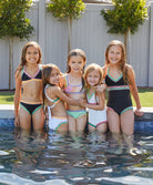 5 girls wearing different colored swimsuits standing in a pool.