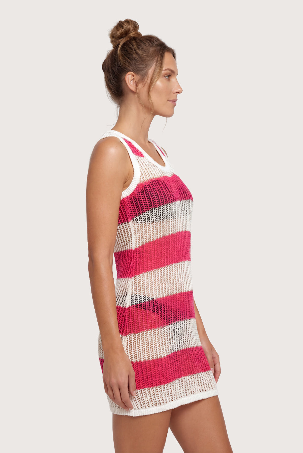 Woman wearing a pink and white striped crochet dress on a plain background