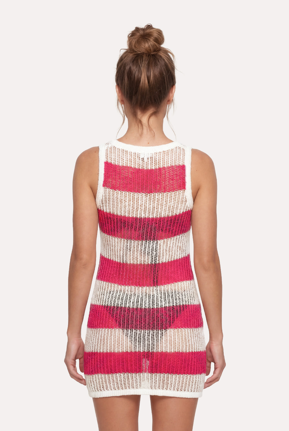 Woman wearing a sleeveless dress with pink and beige striped pattern on a white background