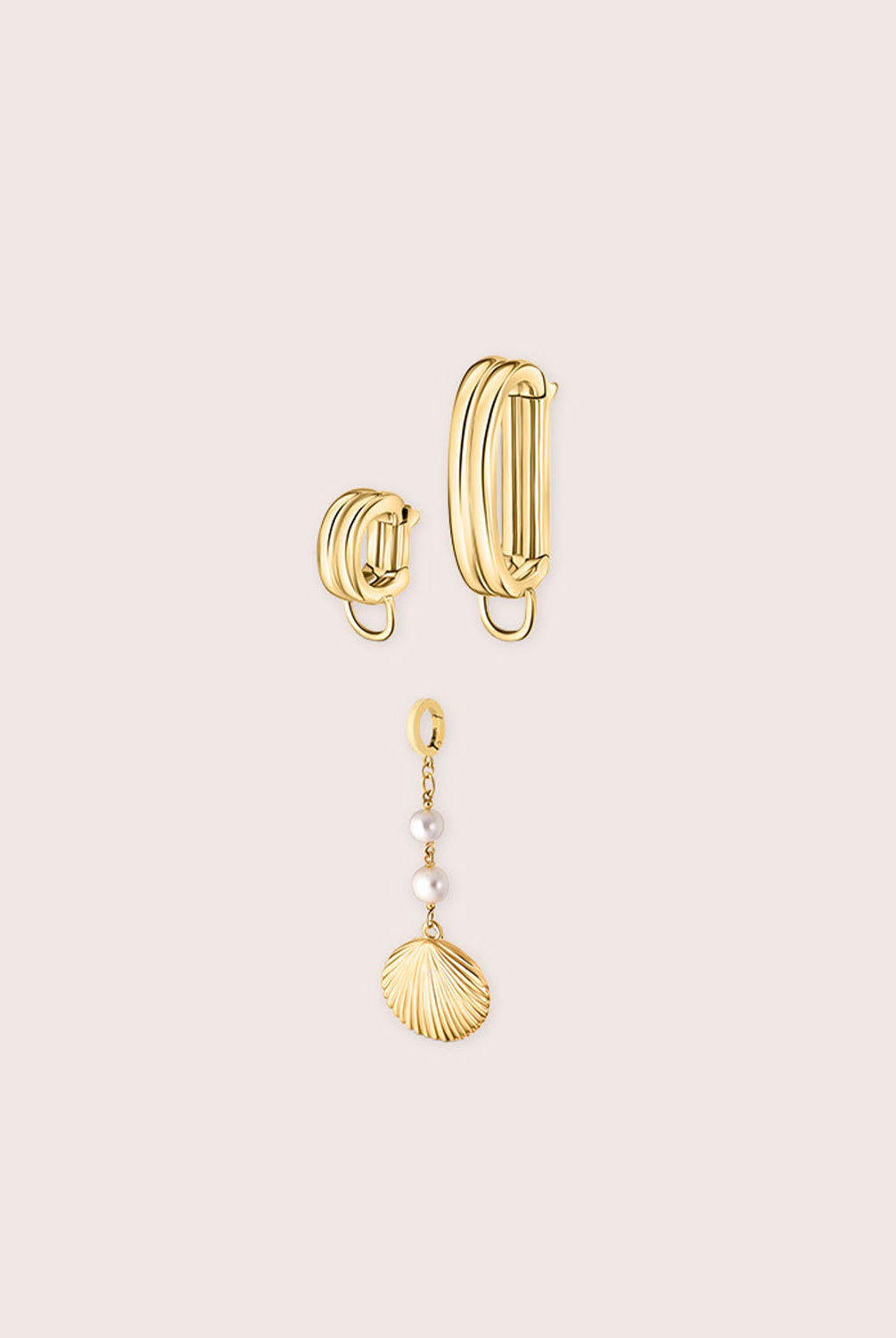 Gold bikini jewelry with a shell against a white wall.