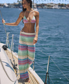 A woman wearing a striped triangle bikini top and matching pants standing on a boat out in the ocean.