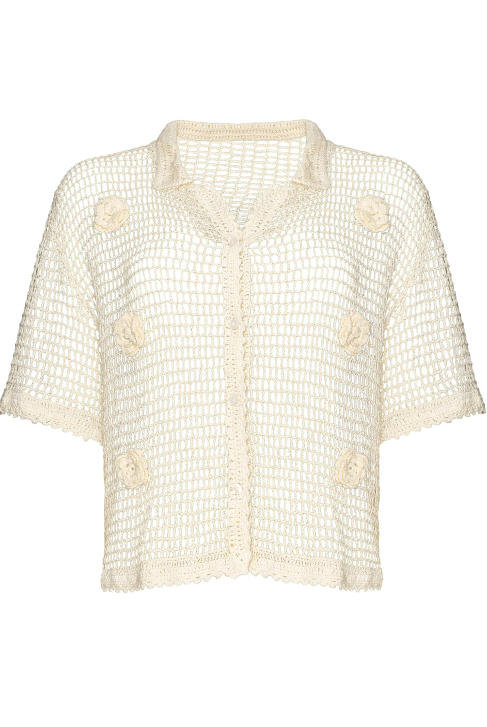 An ivory knit shirt with flower details against a white wall.