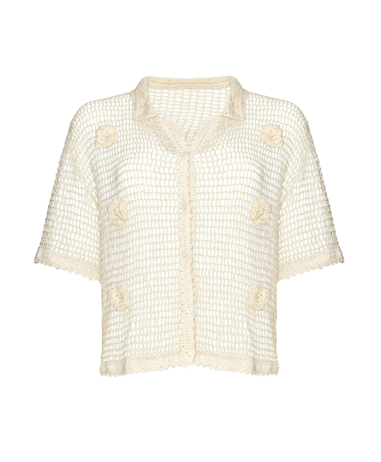 An ivory knit shirt with flower details against a white wall.
