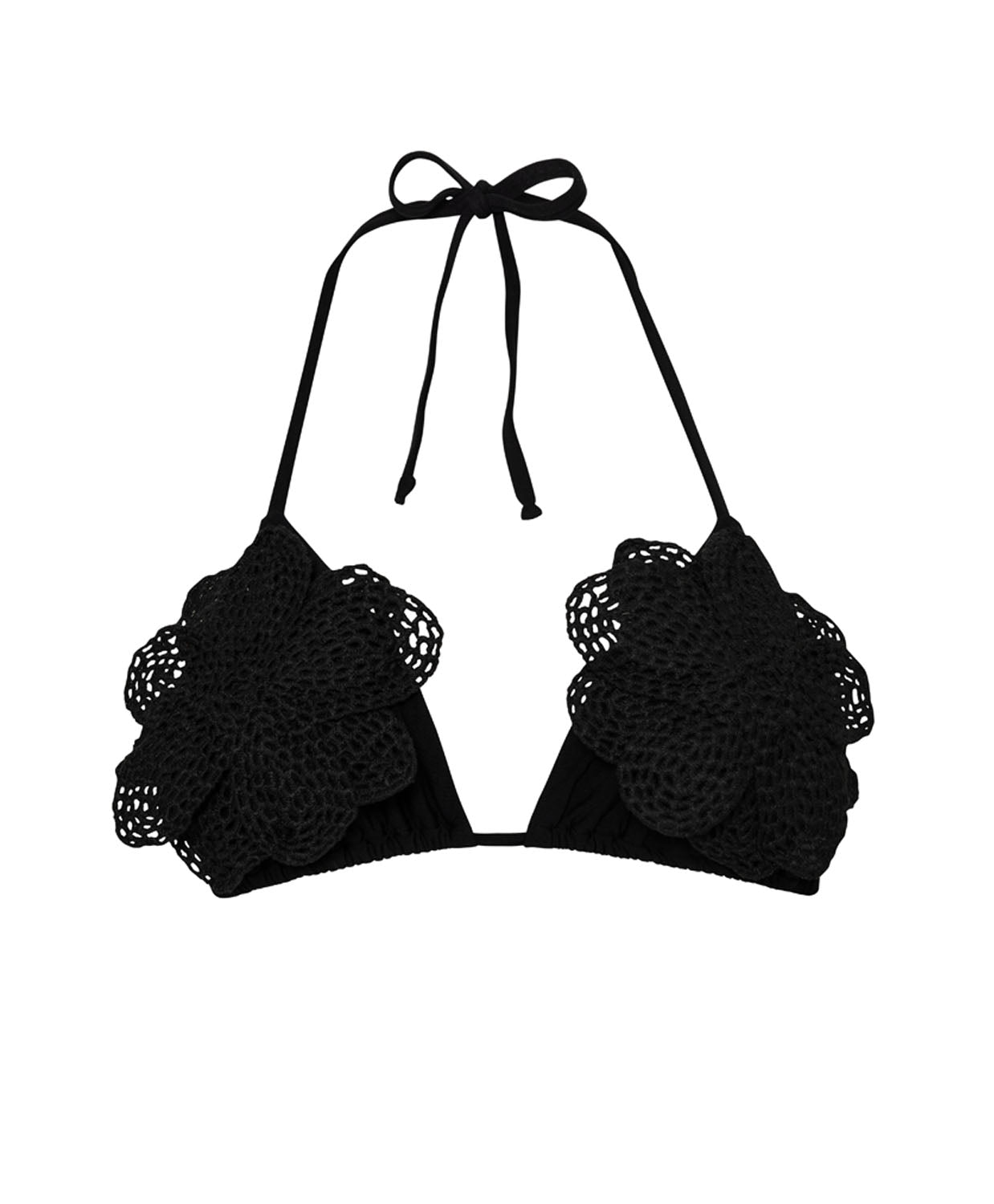 A black bikini triangle top against a white wall background.