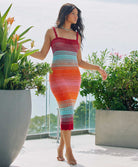 A woman wearing a midi length knit dress standing outside new flowers.
