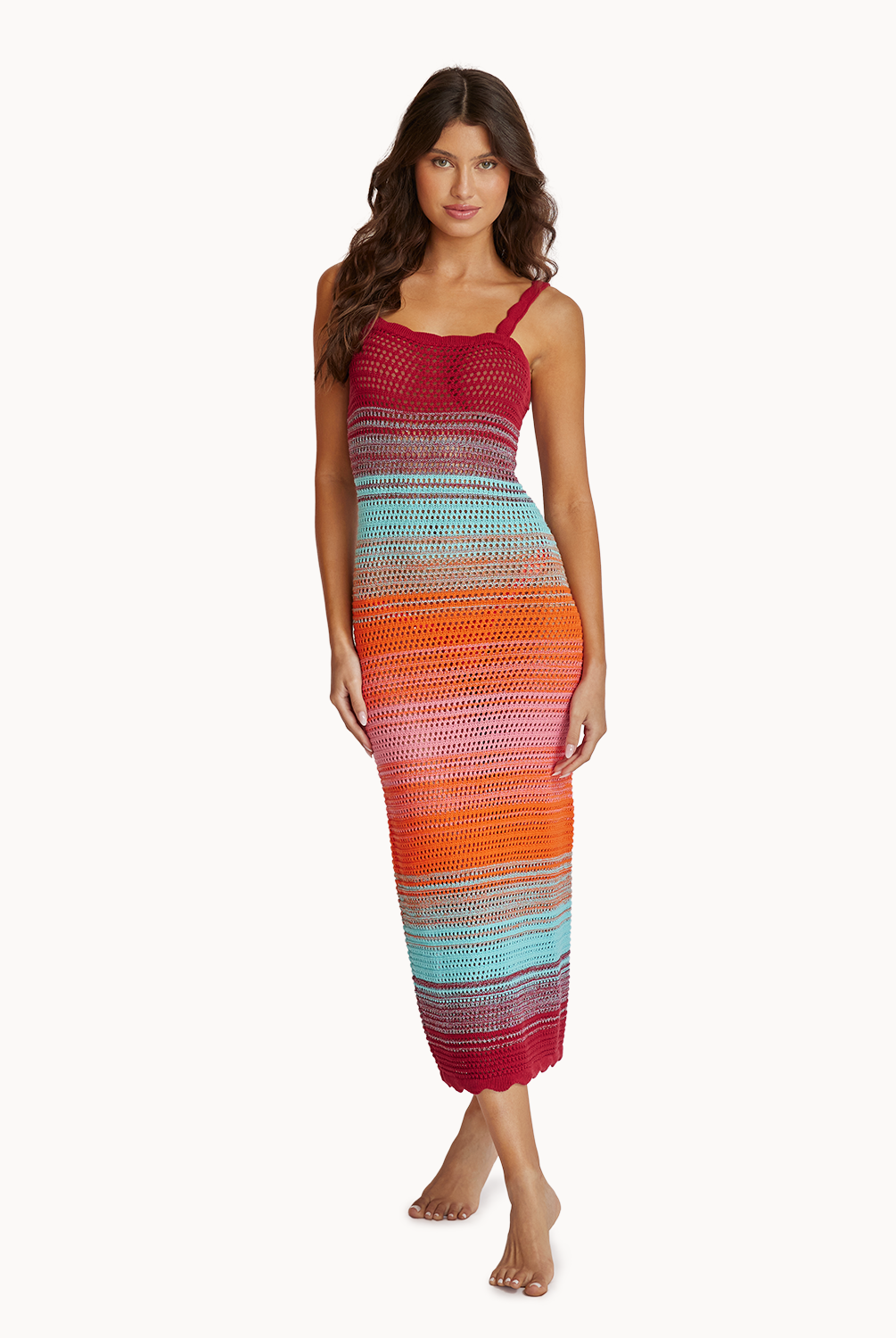 A woman wearing a midi length knit dress standing against a white wall.