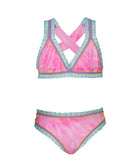 A pink embroidered bikini against a white wall.