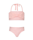 A light pink kids bikini with a bow against a white wall.