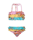 A multi colored floral kids bikini against a white wall.
