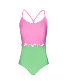 A pink and green one piece swim suit against a white wall.