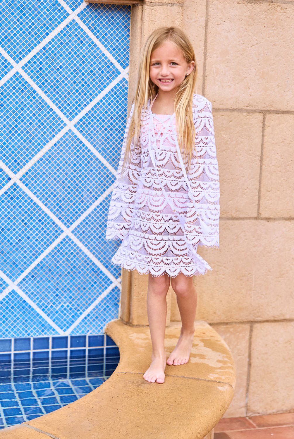 A blonde girl wearing a white long sleeve lace dress.