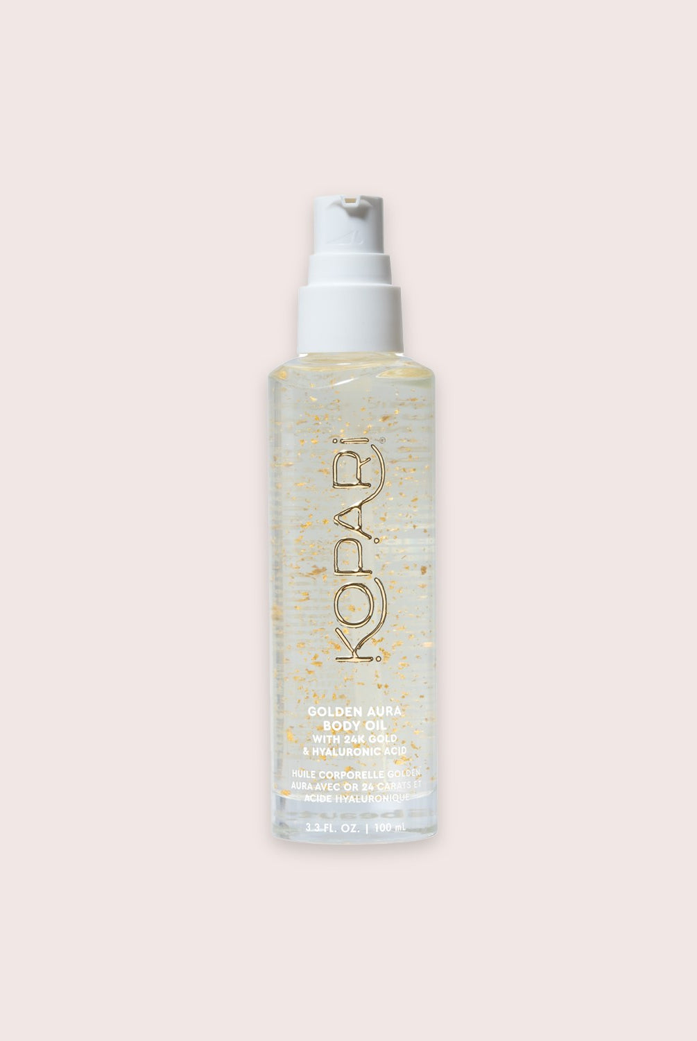 A tube of body oil with gold glitter against a white wall.