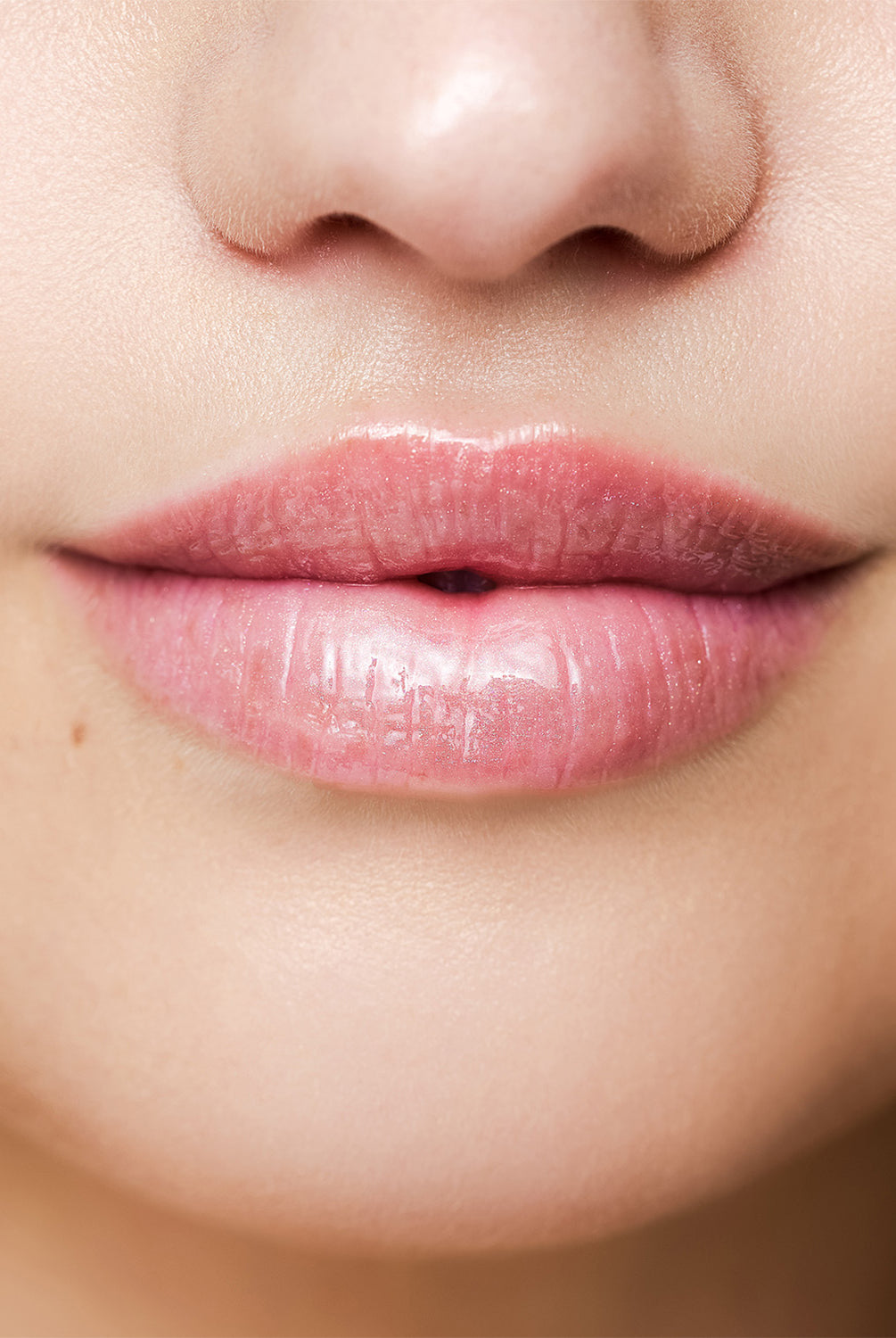 Close up shot of a woman wearing pink lip gloss.