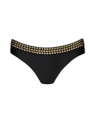 Black bikini bottoms with gold details against a white wall.