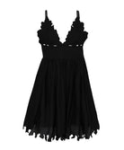 A short black dress against a white wall background.