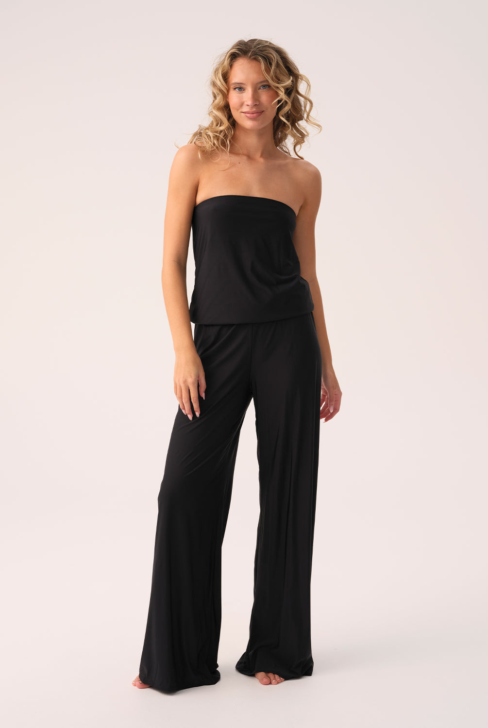Woman wearing a black strapless jumpsuit on a white background