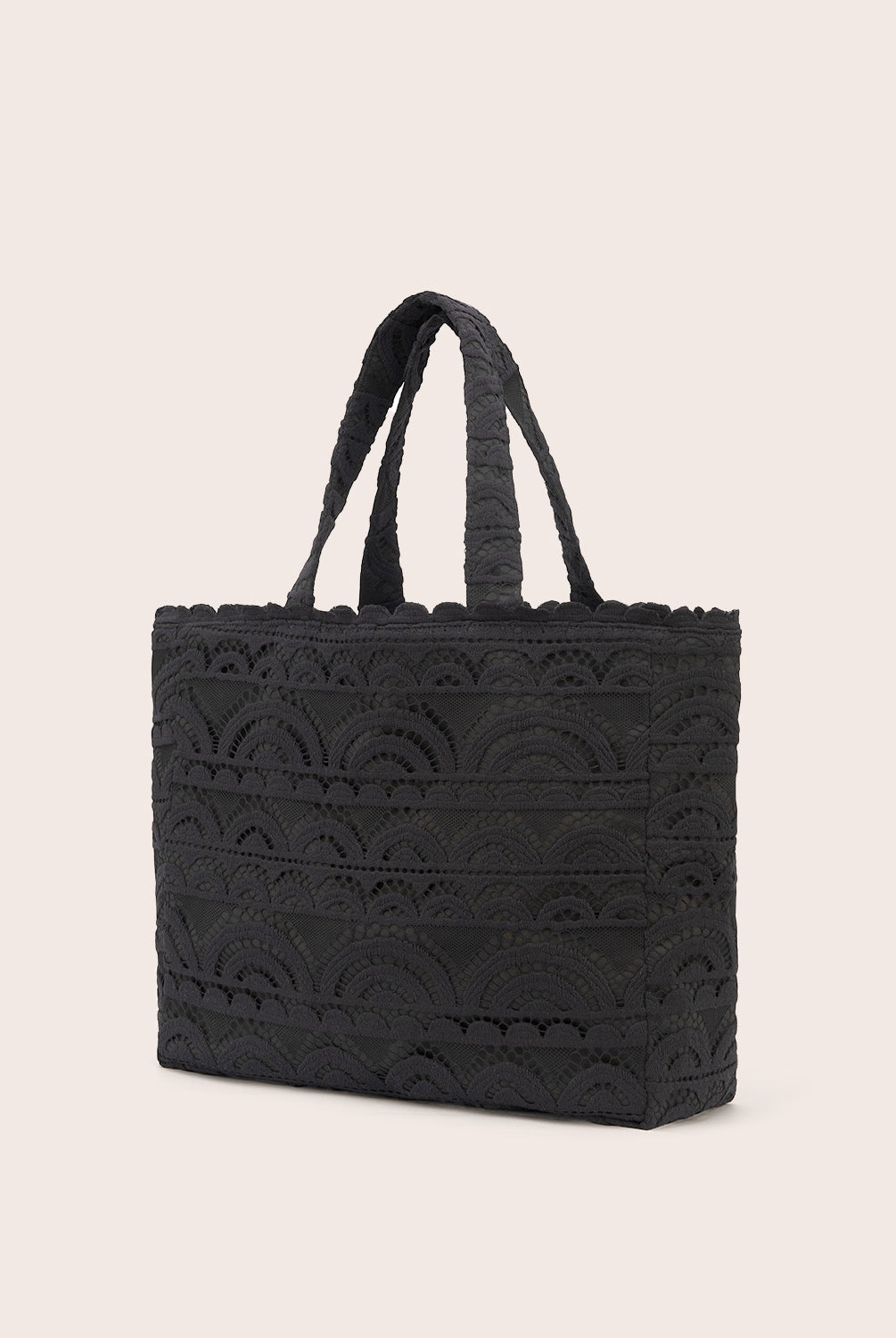 A black lace tote with scalloped trim against a white wall