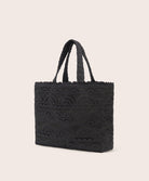 A black lace tote with scalloped trim against a white wall